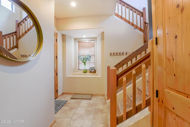 entryway with light tile patterned floors, stairway, and baseboards