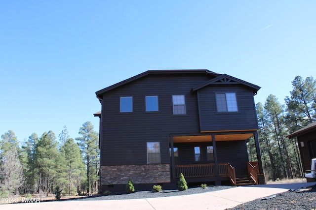 view of front facade with crawl space, stone siding, and a porch