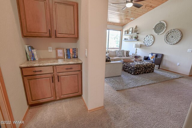 interior space featuring wooden ceiling, baseboards, a ceiling fan, and light colored carpet