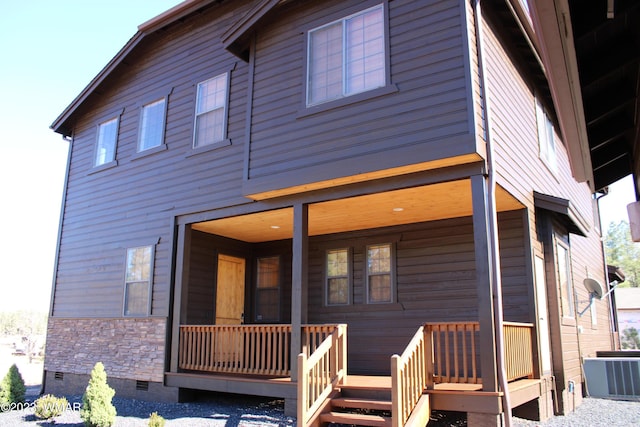 back of house featuring stone siding, crawl space, and central AC unit