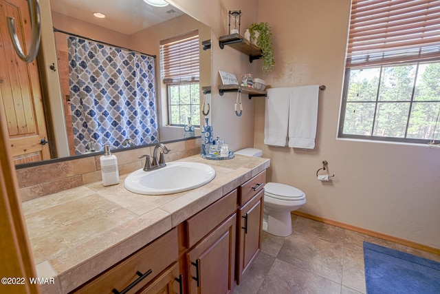 full bath featuring toilet, vanity, and baseboards