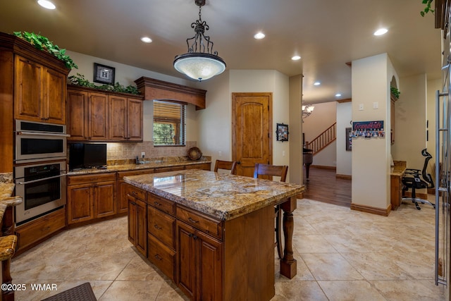 2320 Chandelle Ln, Overgaard, AZ 85933 - kitchen with stainless steel double oven, a breakfast bar, light stone countertops, a kitchen island, and backsplash