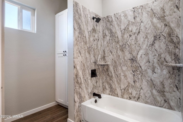 bathroom featuring tub / shower combination, baseboards, and wood finished floors