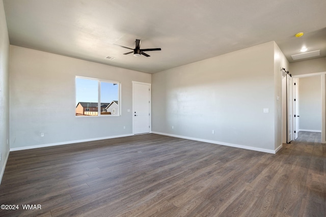 empty room with ceiling fan, attic access, baseboards, and dark wood-style flooring