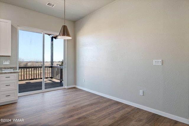 unfurnished dining area featuring dark wood-style flooring, visible vents, and baseboards