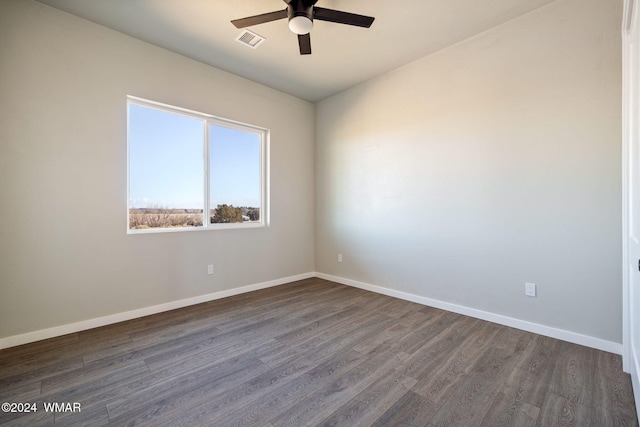 unfurnished room with a ceiling fan, visible vents, dark wood finished floors, and baseboards