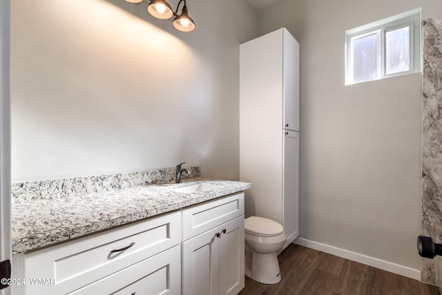 bathroom with toilet, wood finished floors, vanity, and baseboards