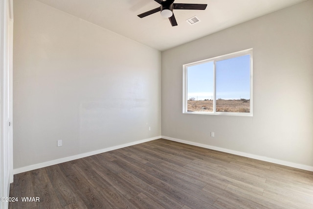 unfurnished room featuring dark wood-style floors, a ceiling fan, visible vents, and baseboards