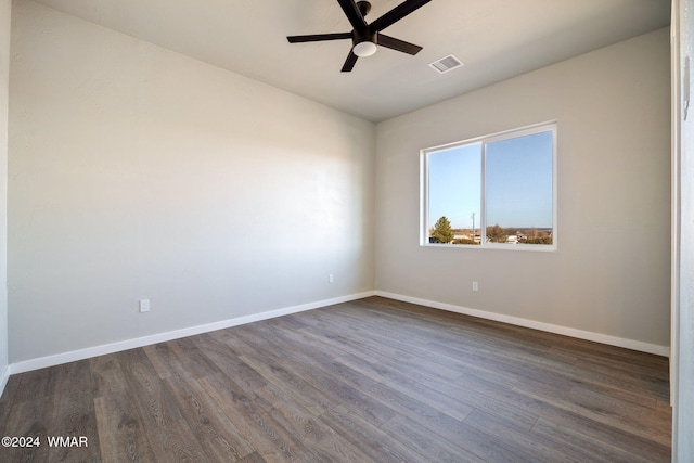 empty room with a ceiling fan, dark wood-style flooring, visible vents, and baseboards