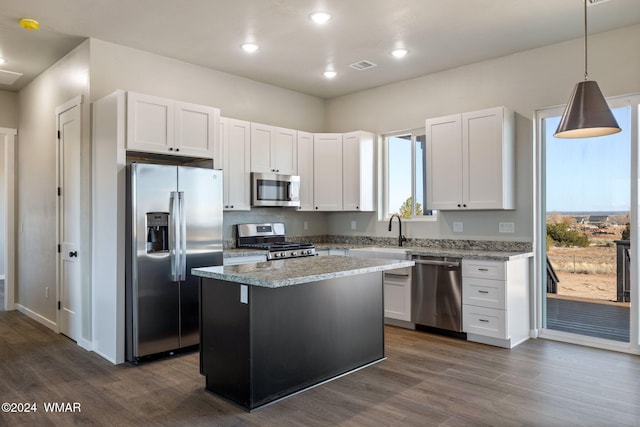 kitchen with a center island, pendant lighting, stainless steel appliances, visible vents, and white cabinetry