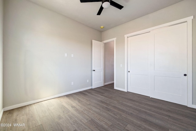 unfurnished bedroom with ceiling fan, a closet, dark wood finished floors, and baseboards