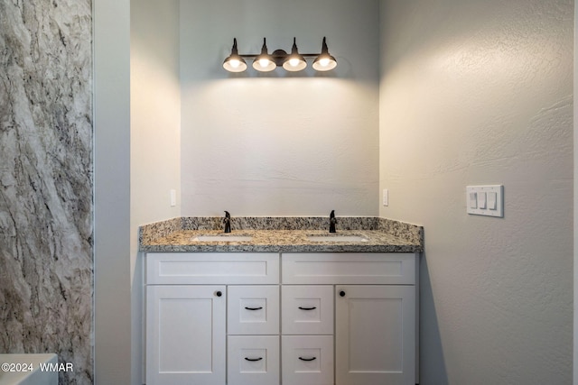 bathroom with a textured wall, double vanity, and a sink