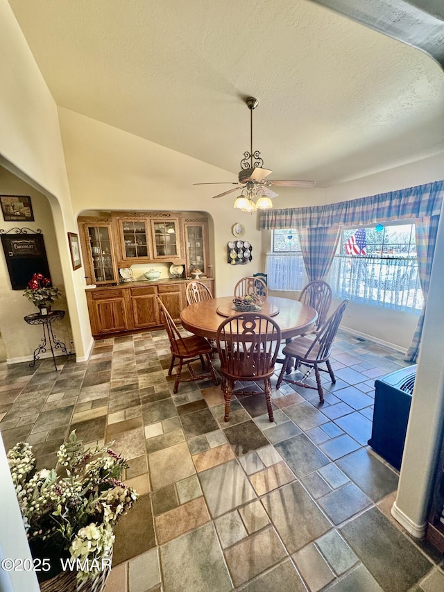 6843 Lucky Ln, Show Low, AZ 85901 - dining space featuring ceiling fan, arched walkways, a textured ceiling, vaulted ceiling, and dark stone finish flooring
