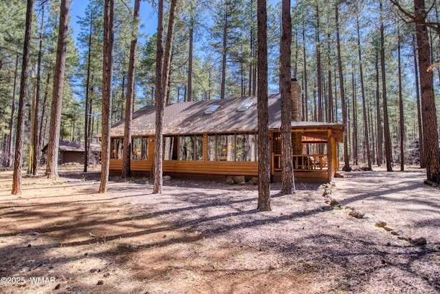 exterior space with a sunroom, a wooden deck, and a chimney