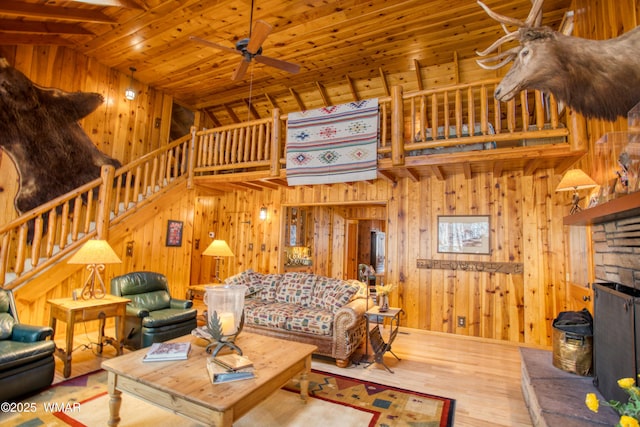 living room with wood ceiling, wood walls, stairway, ceiling fan, and wood finished floors