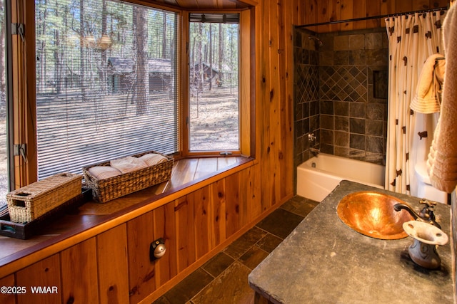 full bath featuring vanity, shower / bathing tub combination, stone finish flooring, wood walls, and baseboards