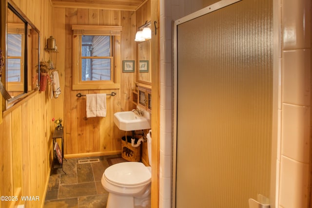 bathroom featuring toilet, visible vents, a shower stall, and wood walls