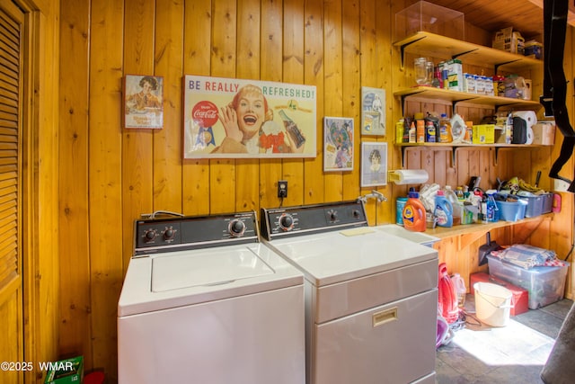 clothes washing area featuring wood walls, laundry area, and washing machine and dryer