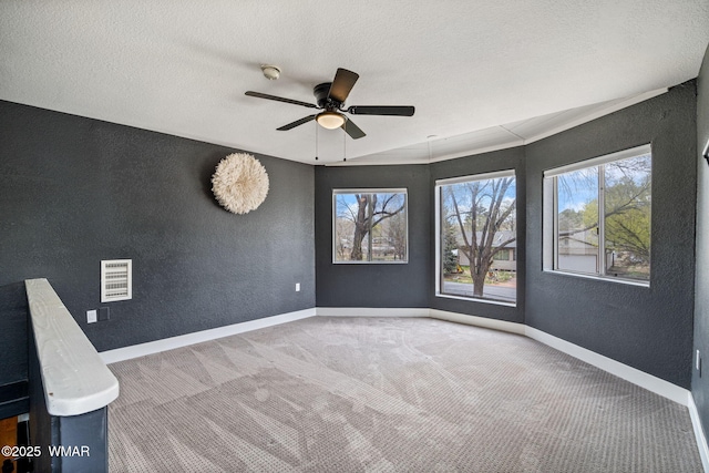 carpeted spare room with baseboards, a textured ceiling, a textured wall, and ceiling fan