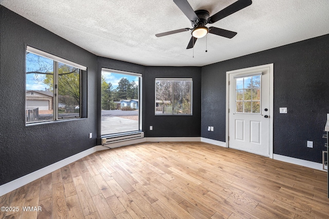 unfurnished room featuring a ceiling fan, a textured ceiling, wood finished floors, baseboards, and a textured wall