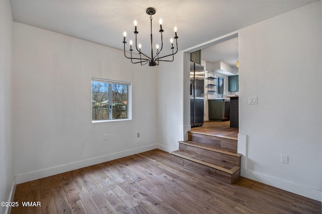 interior space featuring stairs, baseboards, a notable chandelier, and wood finished floors