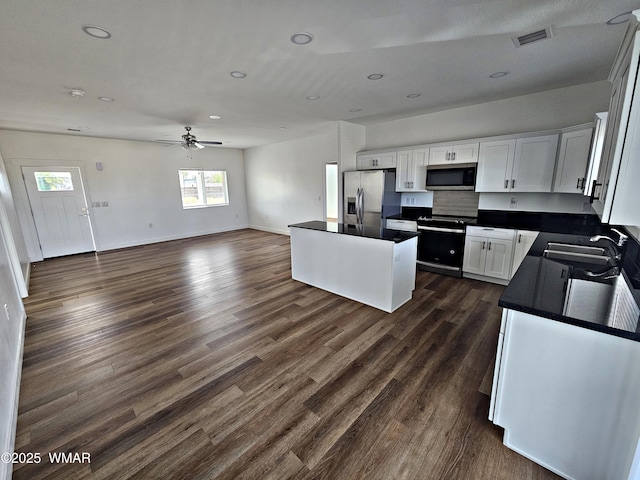 kitchen with dark countertops, ceiling fan, a sink, stainless steel appliances, and visible vents
