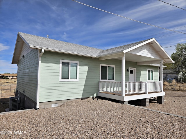 view of front of property with fence, central AC unit, and roof with shingles