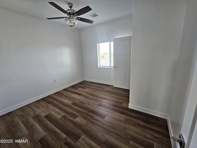 empty room with visible vents, a ceiling fan, baseboards, and dark wood-style floors