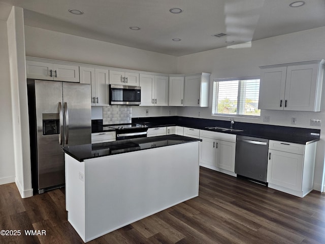 kitchen featuring visible vents, a center island, white cabinetry, a sink, and appliances with stainless steel finishes