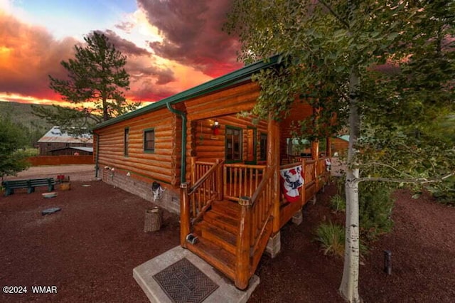 property exterior at dusk featuring crawl space, a deck, and log siding