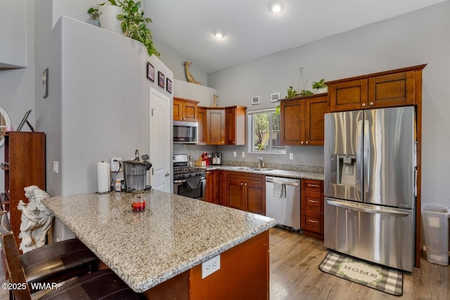 20 N Fox, Show Low, AZ 85901 - kitchen with stainless steel appliances, a peninsula, light stone counters, light wood finished floors, and a kitchen breakfast bar