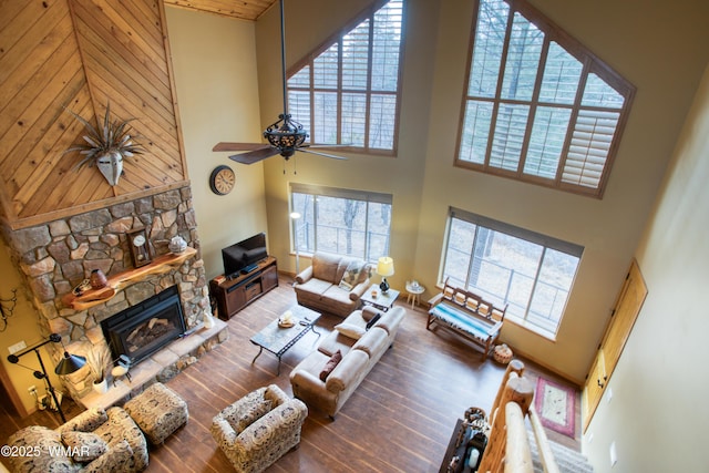 living area featuring a stone fireplace, wood finished floors, and a high ceiling