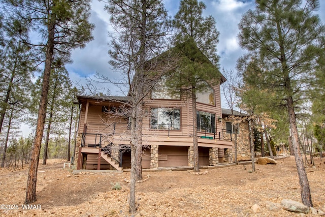 back of house featuring stone siding and stairway