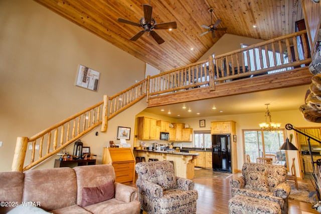 living area featuring high vaulted ceiling, light wood finished floors, stairway, and wood ceiling