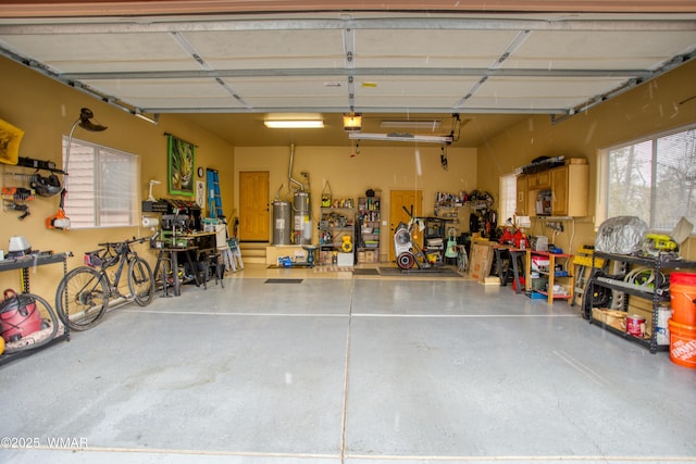 garage featuring a garage door opener, strapped water heater, water heater, and a workshop area