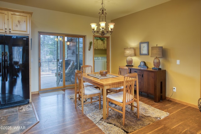 dining space with a notable chandelier, dark wood finished floors, baseboards, and separate washer and dryer