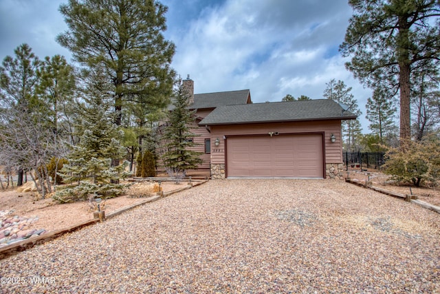 view of front of property with roof with shingles, a chimney, an attached garage, stone siding, and driveway