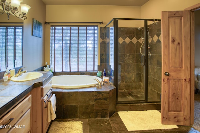 full bathroom featuring a garden tub, vanity, a shower stall, and an inviting chandelier