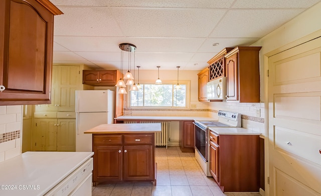 kitchen featuring white appliances, hanging light fixtures, decorative backsplash, and a drop ceiling