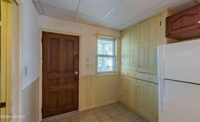 interior space with a paneled ceiling, wooden walls, and light tile patterned floors