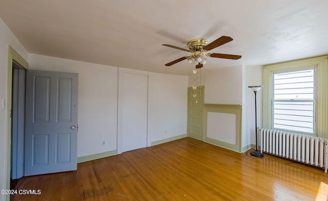 unfurnished room featuring hardwood / wood-style flooring, ceiling fan, and radiator