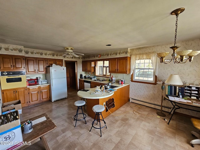 kitchen with pendant lighting, white appliances, baseboard heating, and ceiling fan with notable chandelier