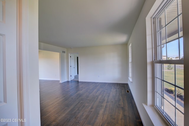 empty room featuring visible vents, baseboards, and dark wood-style flooring