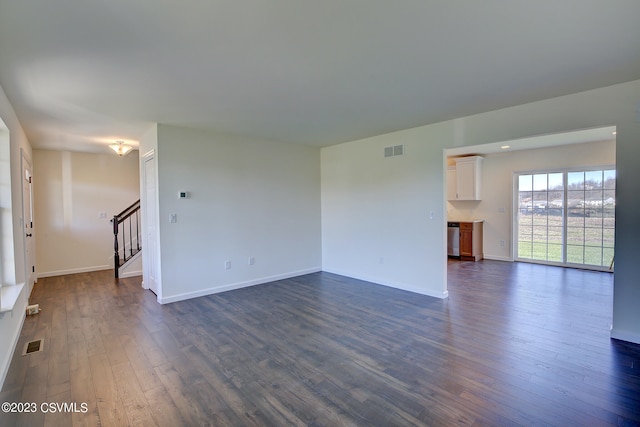 spare room featuring visible vents, baseboards, dark wood-style floors, and stairs