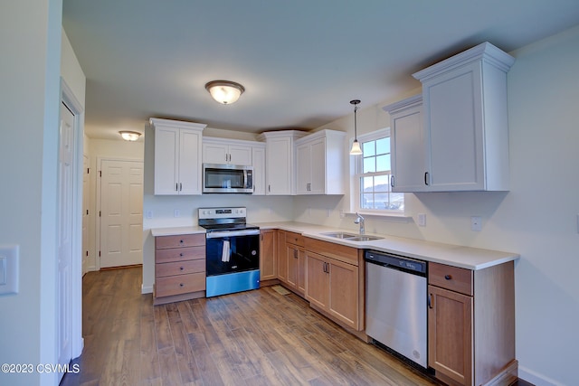 kitchen featuring white cabinets, dark hardwood / wood-style floors, appliances with stainless steel finishes, and hanging light fixtures