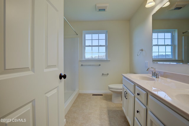 bathroom featuring double sink vanity, toilet, tile flooring, and plenty of natural light