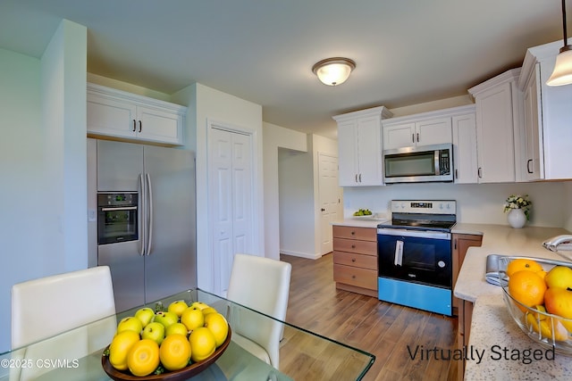 kitchen featuring stainless steel appliances, white cabinets, baseboards, dark wood-style flooring, and hanging light fixtures