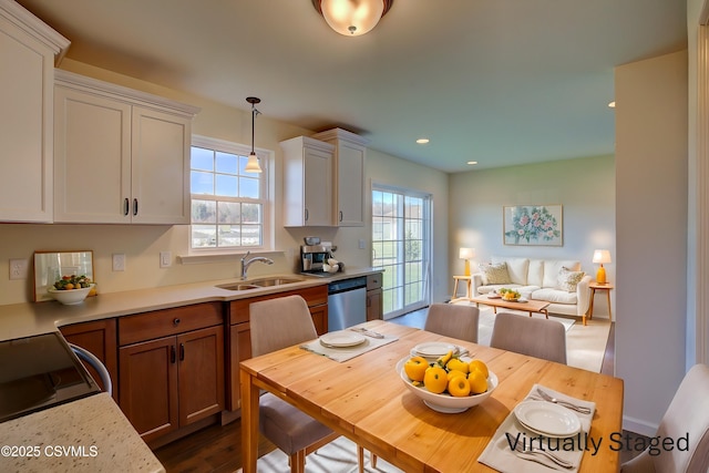 kitchen with a sink, decorative light fixtures, dishwasher, and a wealth of natural light