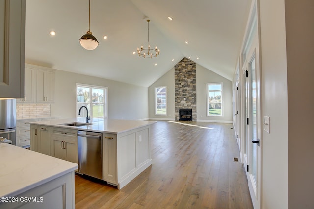 kitchen featuring sink, appliances with stainless steel finishes, a kitchen island with sink, and light wood-type flooring