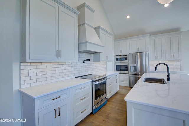 kitchen with tasteful backsplash, sink, stainless steel appliances, lofted ceiling, and white cabinets